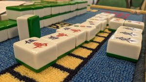 Des pièces du jeu de Mahjong sont visibles sur un tapis de jeu.